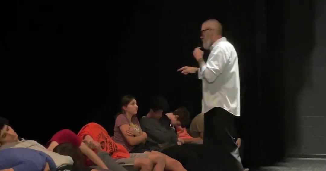 Dennis Timlick guiding hypnotized volunteers on stage during a comedy hypnosis show