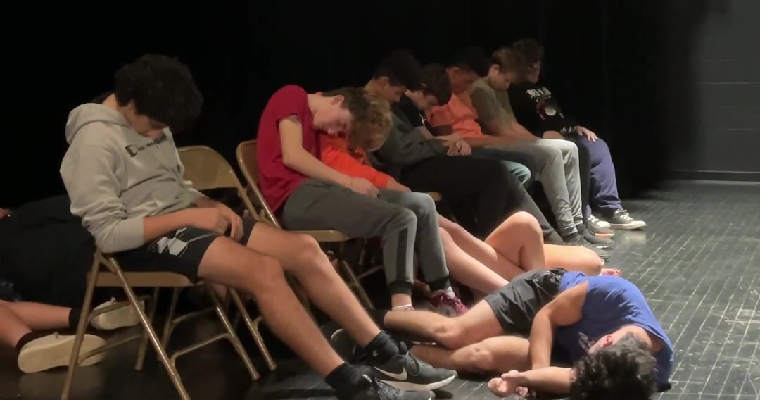 Hypnotized student volunteers asleep on stage during a high school hypnosis show